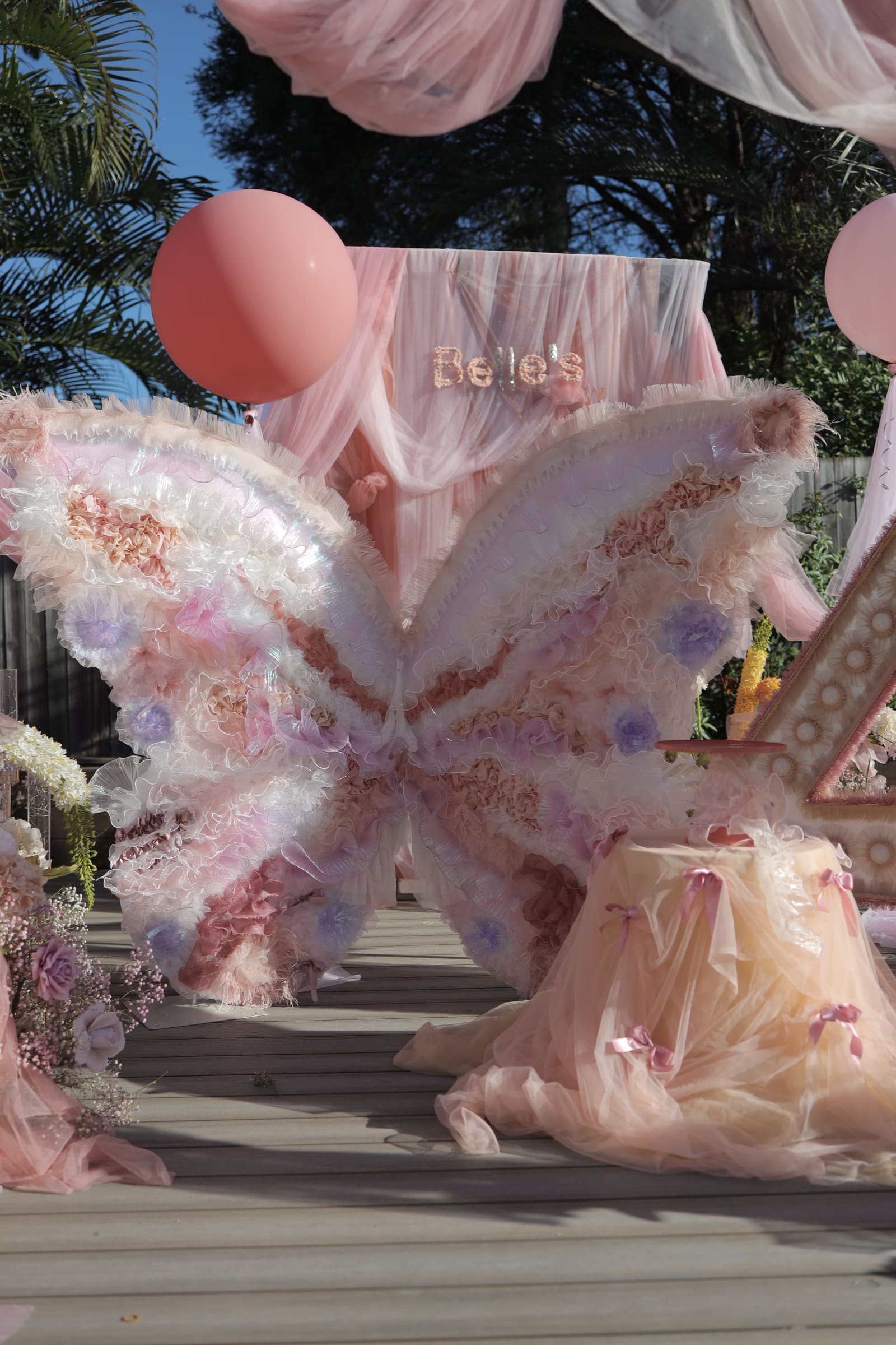 A feathered butterfly installation in blush and lilac with tulle, at a private celebration
