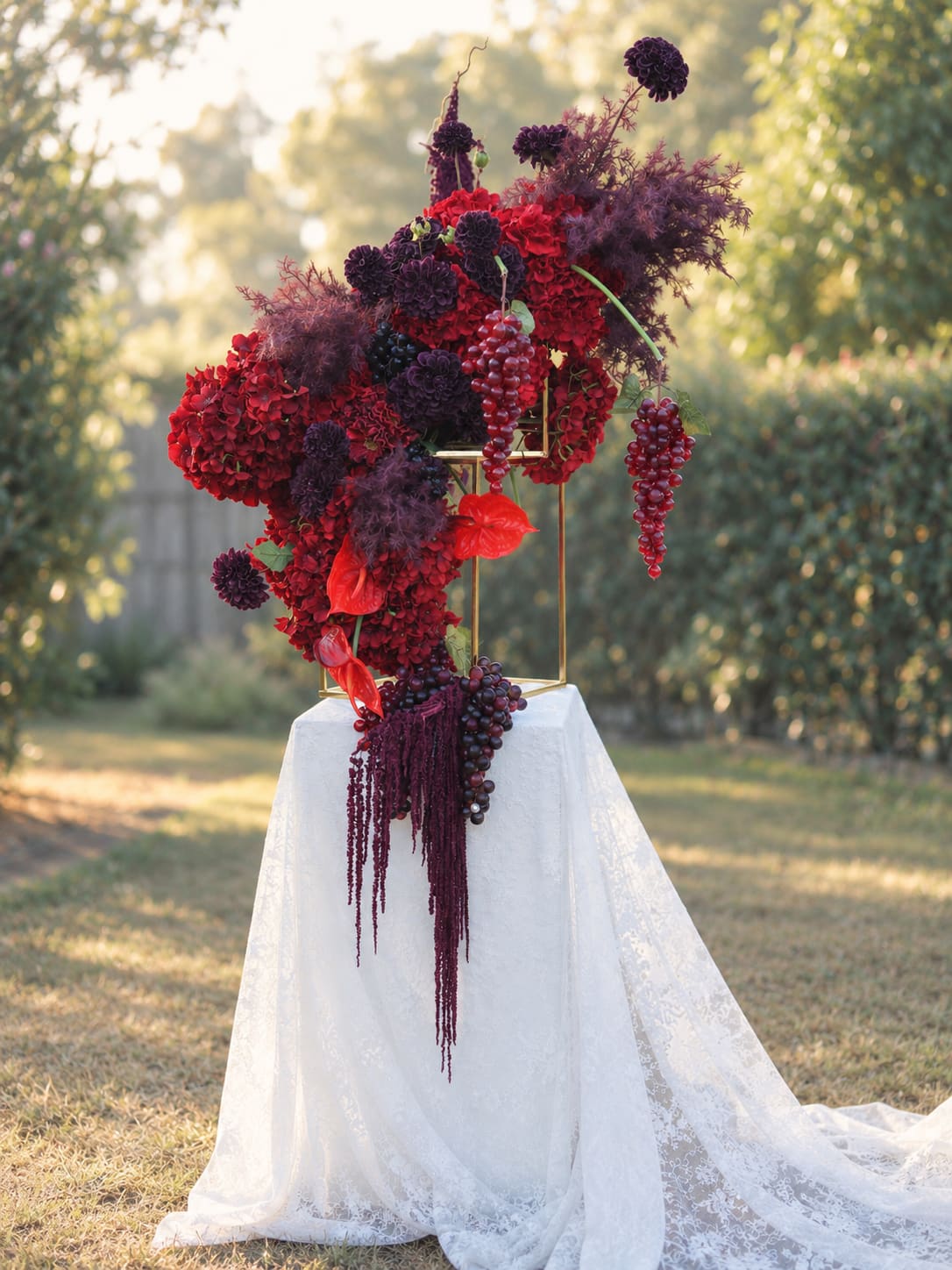 Bordeaux Garden red and burgundy floral installation on a lace-draped plinth outdoors