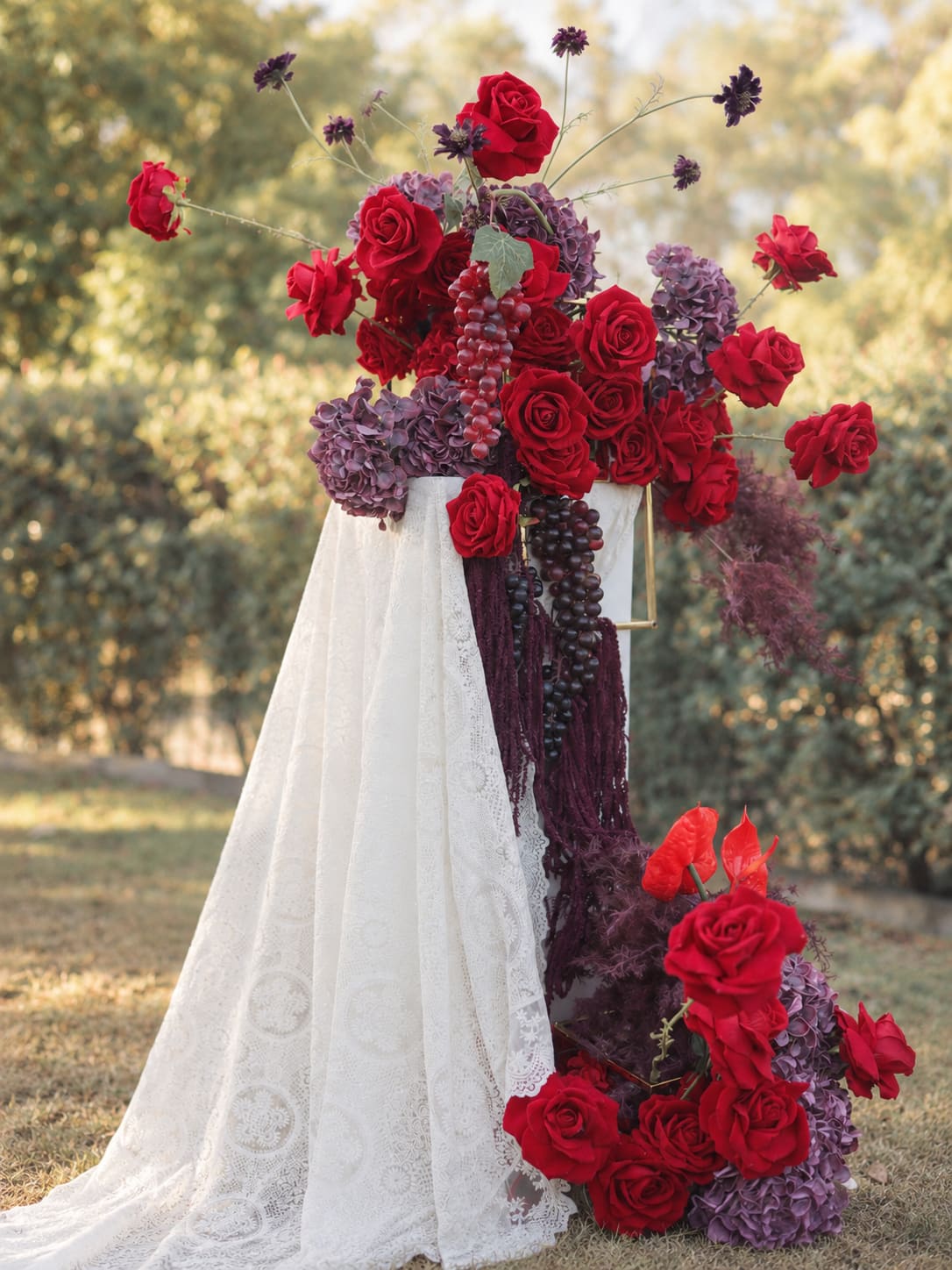 Bordeaux Garden detail showing red roses, burgundy florals and trailing accents over a lace-draped plinth