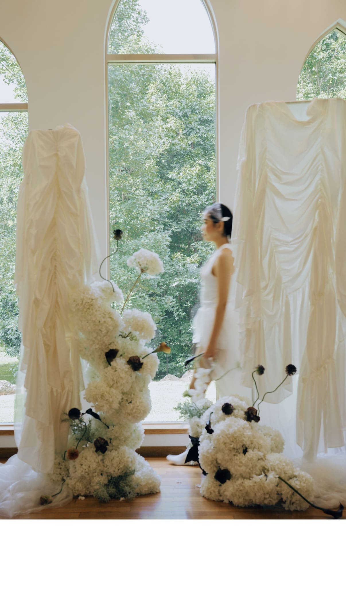 Real photograph of a bride walking beside The Sculpture installation framed by arched chapel windows