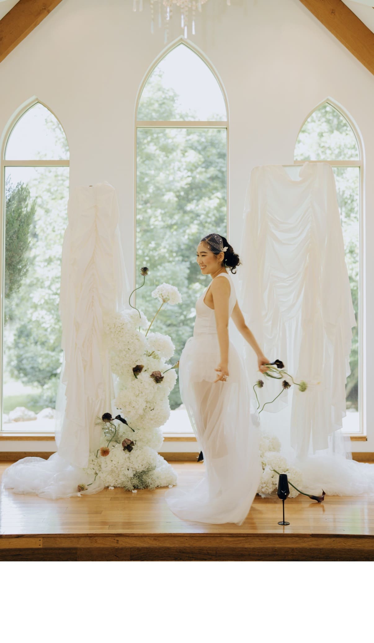 Real photograph of a bride standing among The Sculpture's white florals and soft draping in a chapel