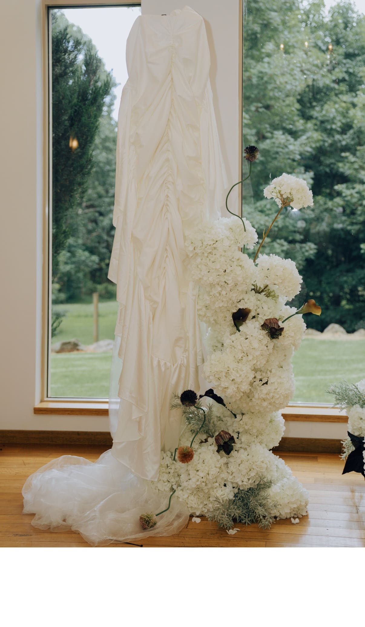 The Sculpture's taller white floral arrangement beside a softly draped backdrop