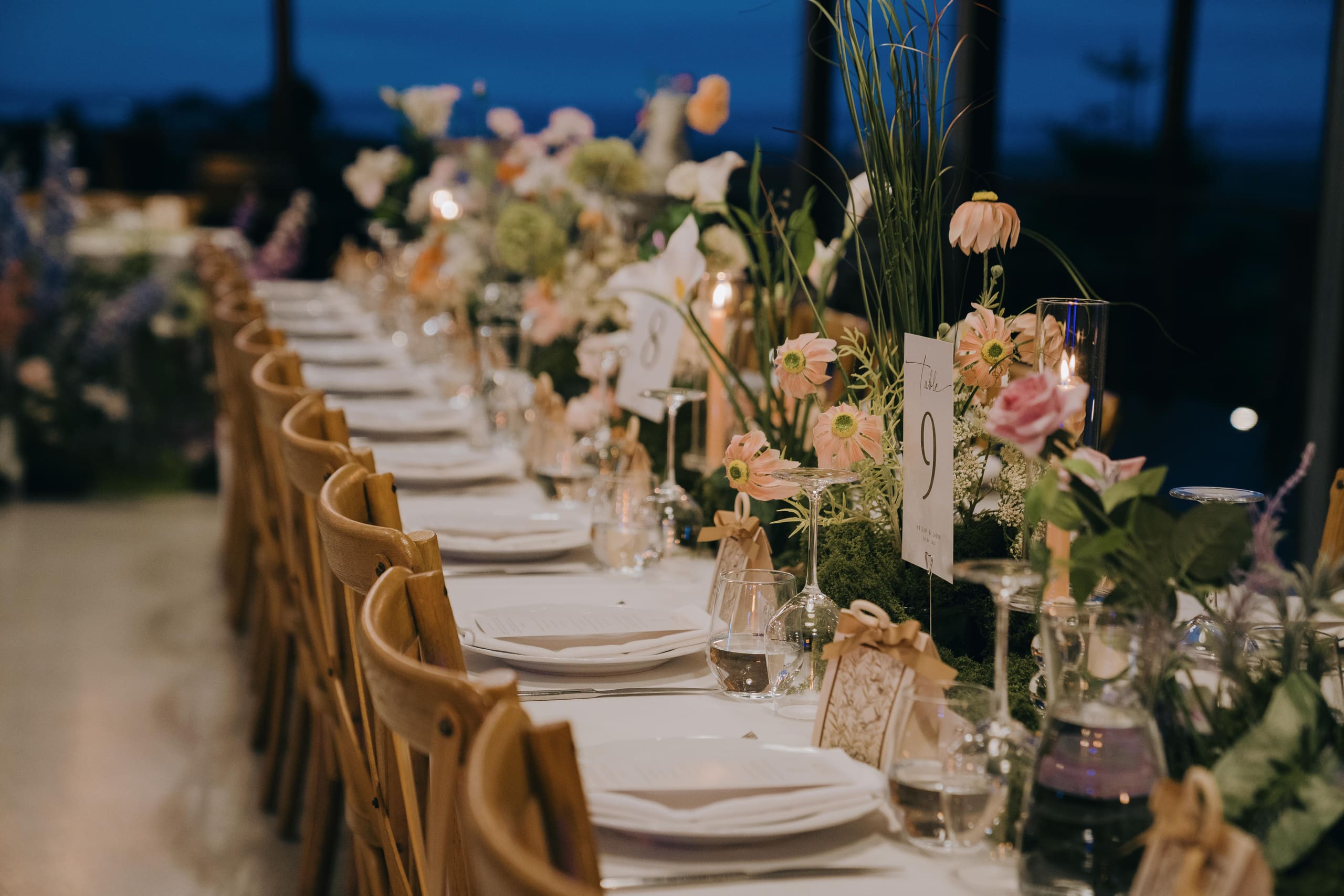 A long table set with pastel florals and candles at dusk