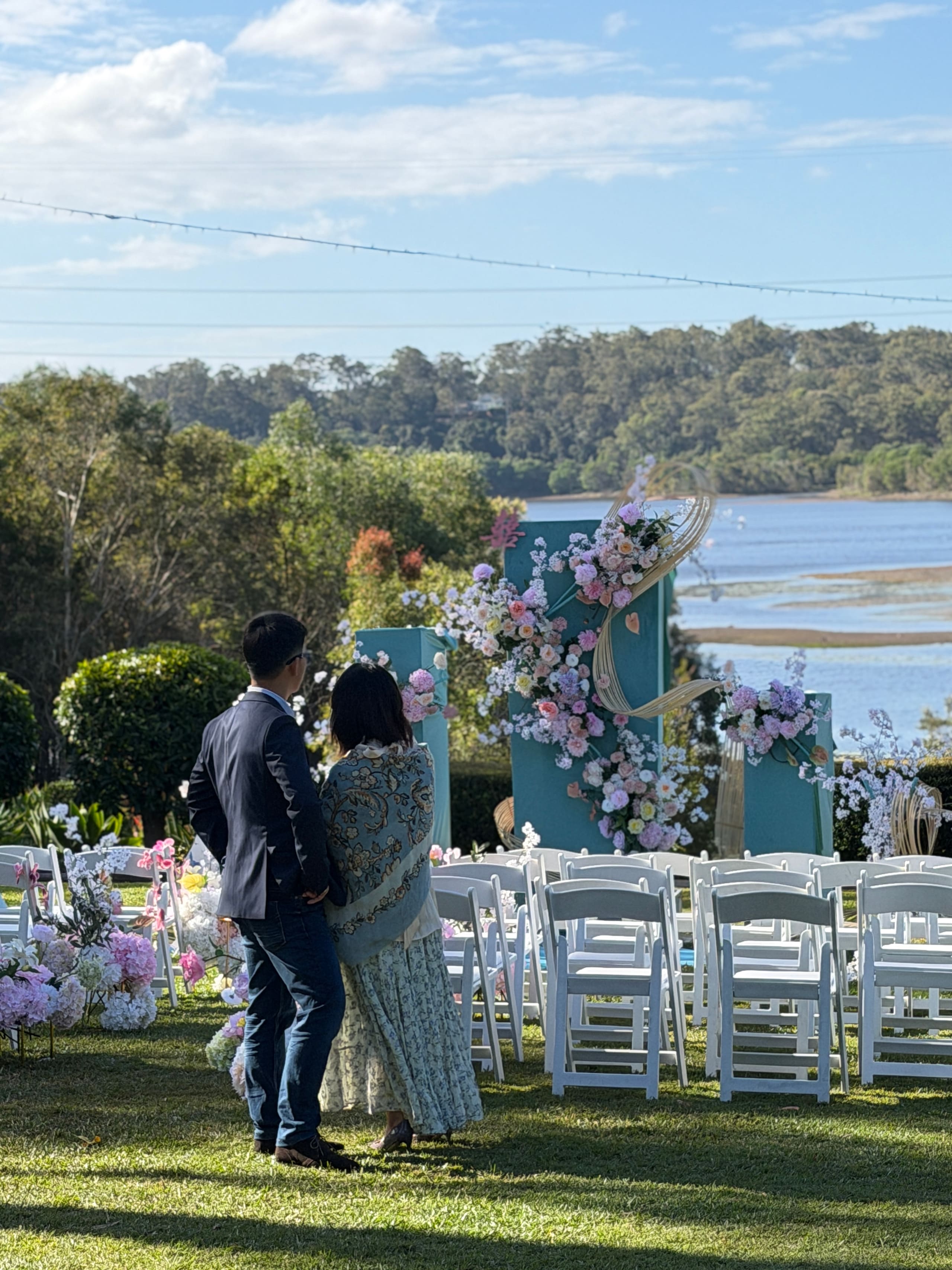 The couple standing by the lake beside the ceremony setting