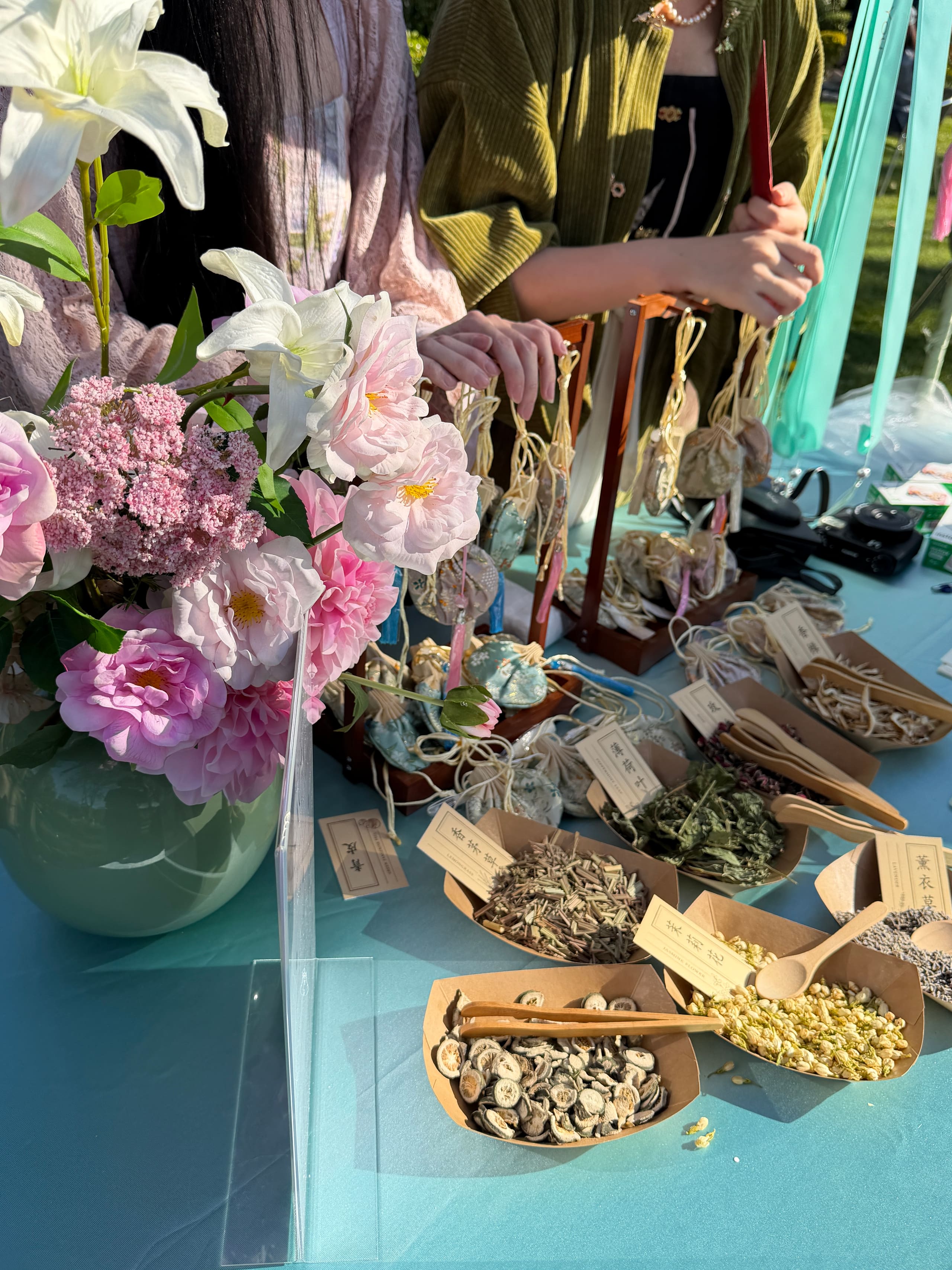 Dried herbs and handmade sachets beside pink and white florals